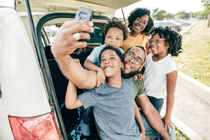 Family of Five, Mom in the back, daughter on the right, baby son on the left, oldest son in the front, all under the at the back of mini van under hood of hatch back trunk